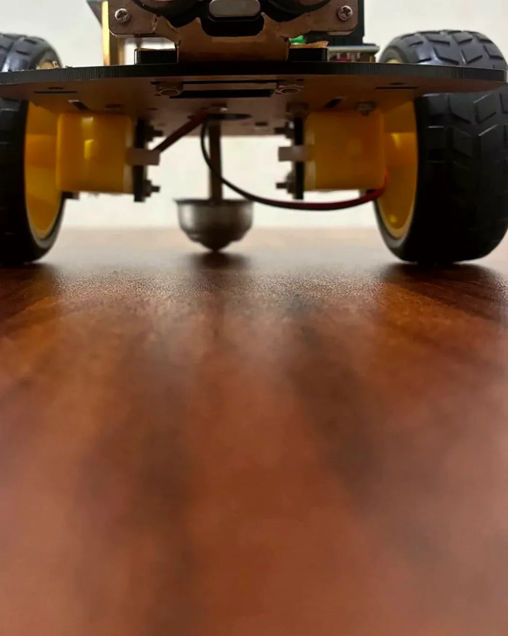 An Arduino robot car from the side, showing its wiring and an ultrasonic sensor