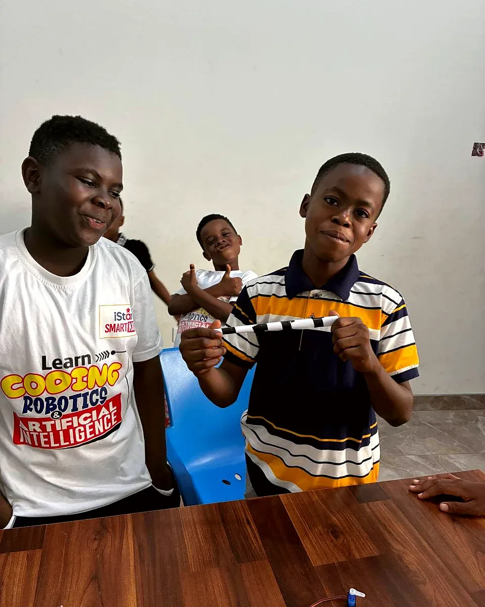 Two students holding up a striped project part and smiling
