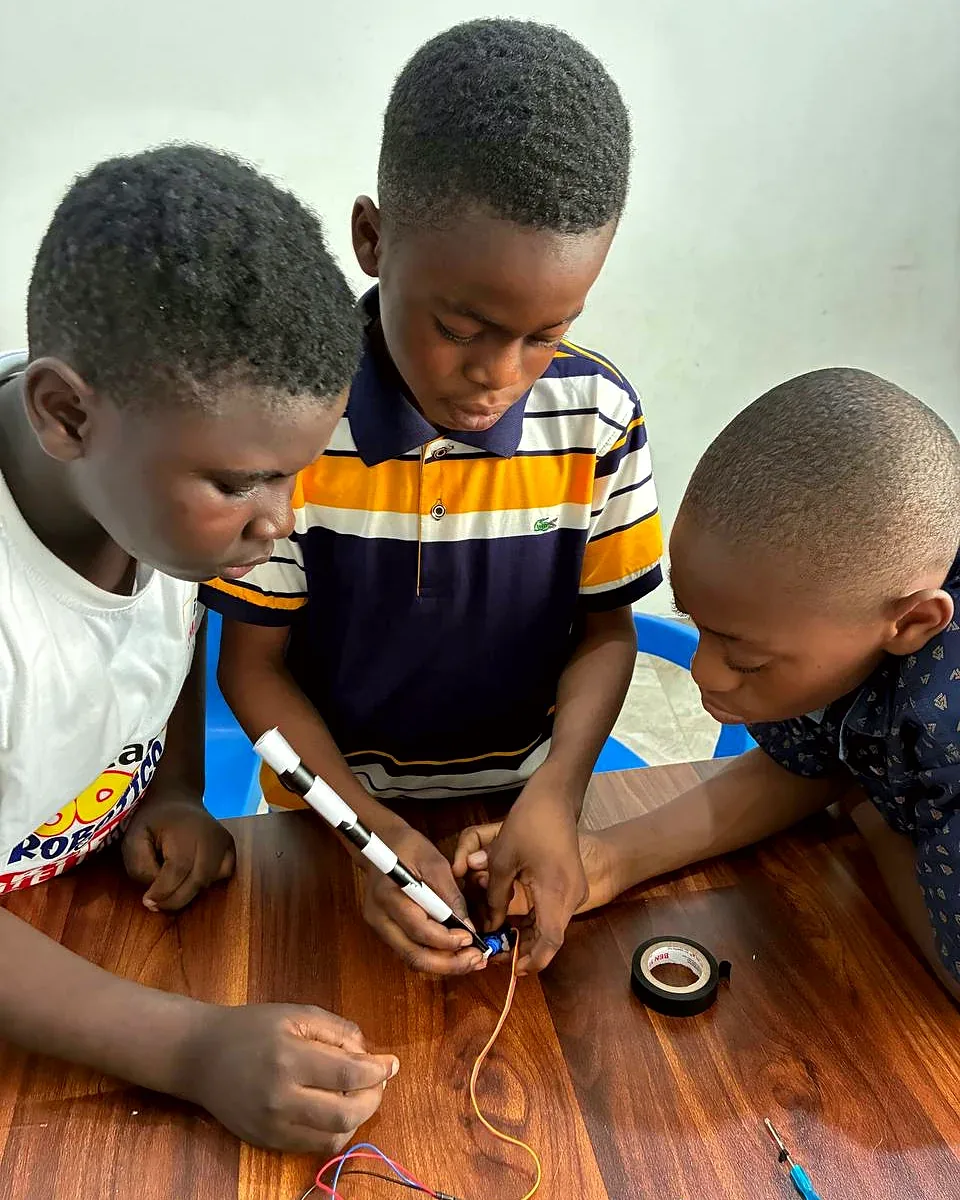 Three students leaning over a table to wire a small circuit together